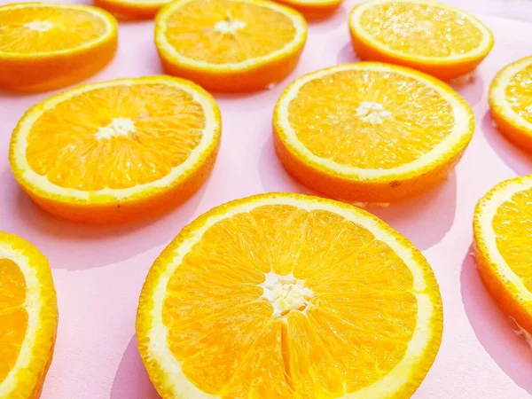 Slices of juicy orange oranges on a bright pink background. — Stock Photo, Image