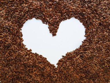 Beyaz arka planda kalp şeklinde keten tohumu