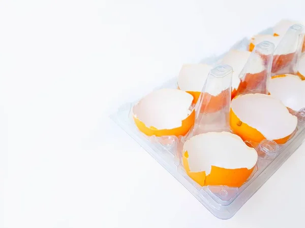Huevos amarillos rotos en una bandeja transparente de plástico sobre un fondo blanco . — Foto de Stock