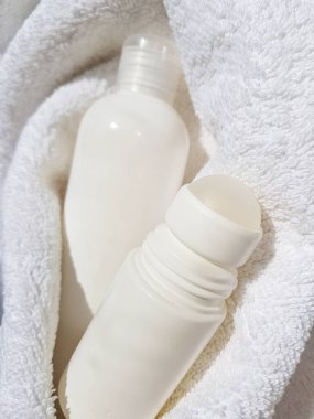 Beyaz yumuşak bir havlunun arka planında kozmetik şişeler var. Marka düzeni için boş etiket. Alıcıların metni için yer.