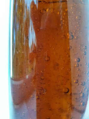 Beyaz zemin üzerinde kahverengi sıvı bir şişede hava kabarcıkları ve marka metin için boşluk.