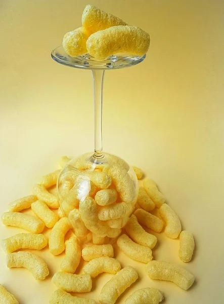 Palitos de maíz en un vaso alto transparente sobre un fondo amarillo . —  Fotos de Stock