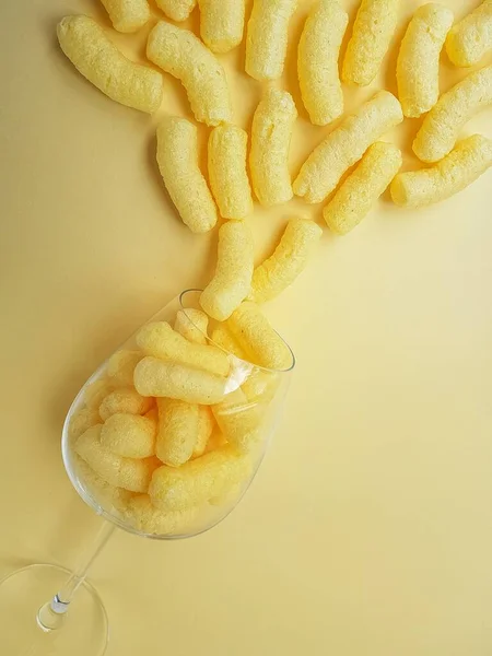 Palitos de maíz dulce amarillo dispersos de un vaso sobre un fondo amarillo. Dulces para niños . —  Fotos de Stock