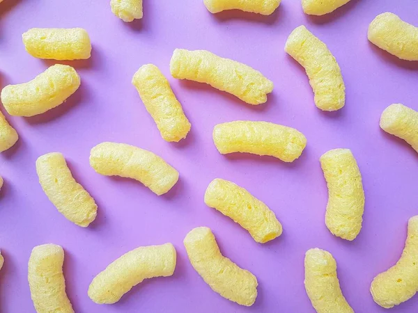 Gelbe Maisstäbchen auf lila Hintergrund. — Stockfoto