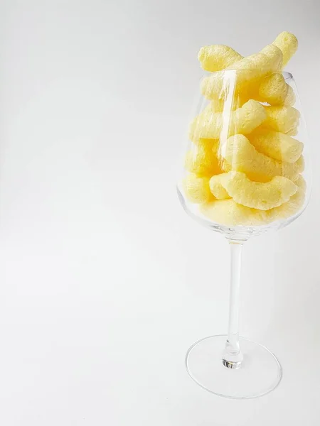 Gele maïsstokjes in een transparant glas op een witte achtergrond. — Stockfoto
