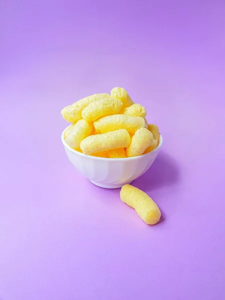 Gelbe Maisstäbchen in einem weißen Teller auf violettem Hintergrund. — Stockfoto
