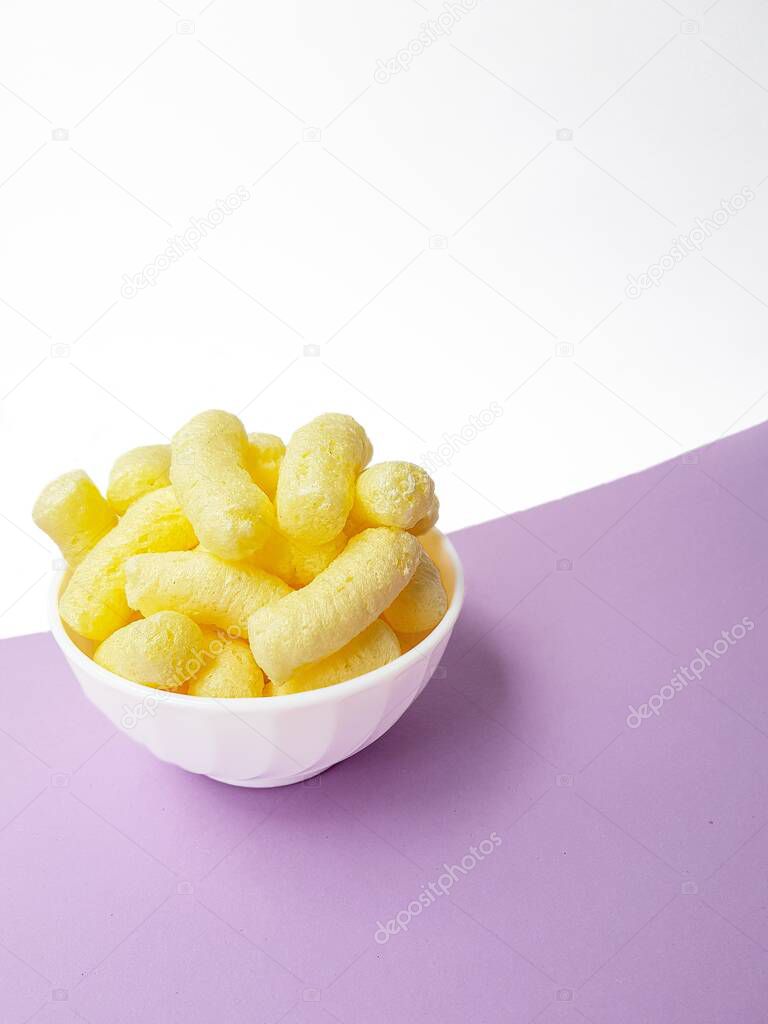 Yellow corn sticks in a white plate on a purple background.