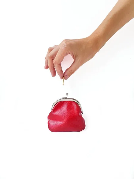 Una mano di donne mette i soldi in una borsa rossa con una serratura di metallo su uno sfondo bianco. Risparmio di denaro. — Foto Stock