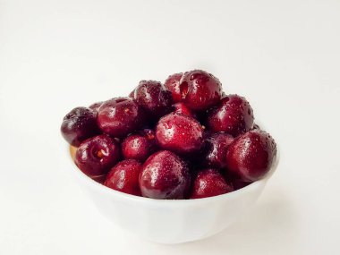 Beyaz zemin üzerinde parlak sulu kırmızı kiraz damlalar halinde su.