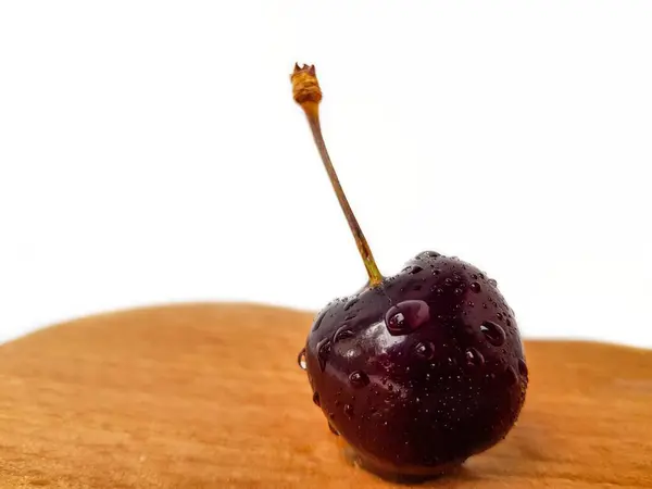 Bright juicy ripe red cherry on a wooden table on a white background with a sprig. — Stock Photo, Image