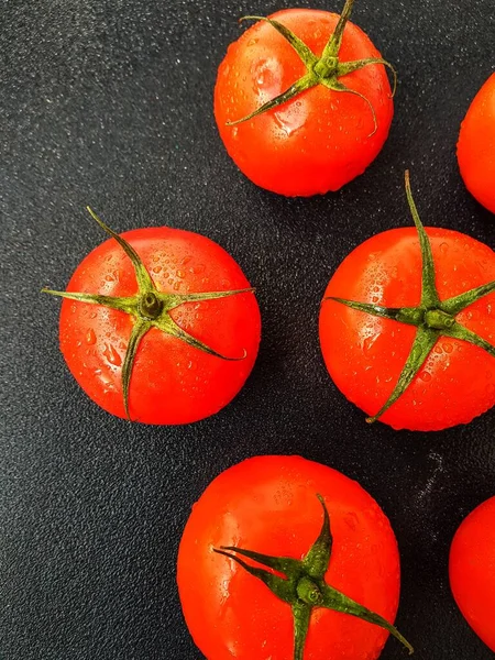 Strahlend saftige rote Tomate auf schwarzem Hintergrund mit Blättern und Stamm. — Stockfoto