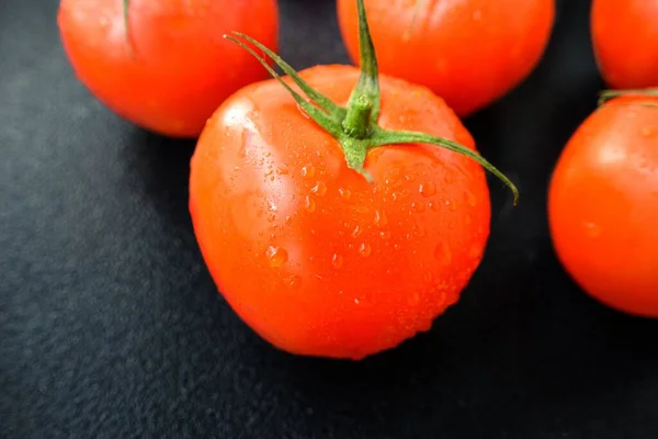 Strahlend saftige rote Tomate auf schwarzem Hintergrund mit Blättern und Stamm. — Stockfoto