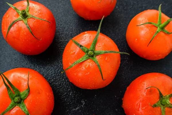 Tomate vermelho suculento maduro com folhas verdes em um fundo escuro. Em gotas de água de tomates, limpas . — Fotografia de Stock