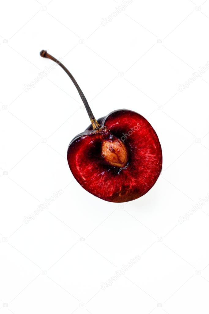 Bright ripe juicy cherry cut in half with a bone inside on a white background.