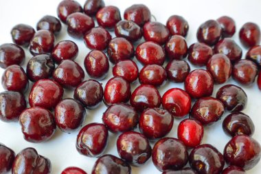 Beyaz bir zemine serpiştirilmiş kırmızı kiraz ve bir damla su..