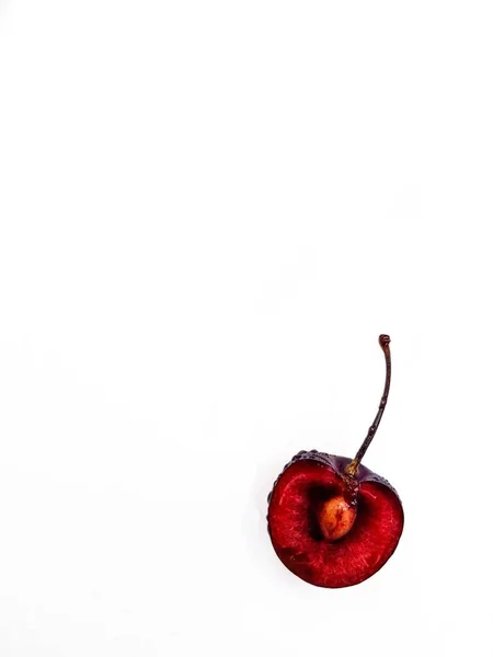 Яркая спелая сочная вишня, разрезанная пополам с костью внутри на белом фоне . — стоковое фото