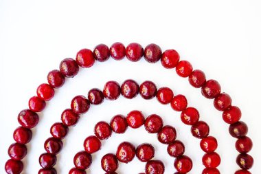 Kırmızı kiraz sulu beyaz arka planda spiral şeklinde serilir..