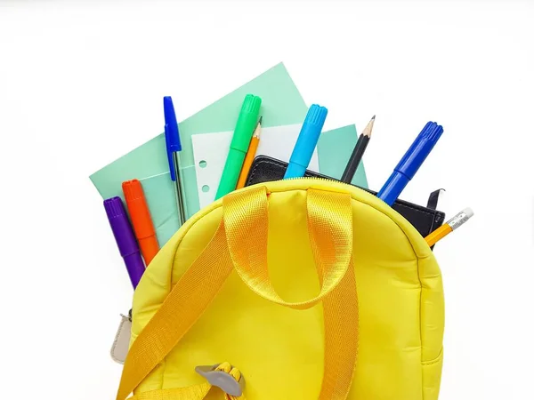Mochila amarela escolar com cadernos e material escolar sobre fundo branco. De volta à escola . — Fotografia de Stock
