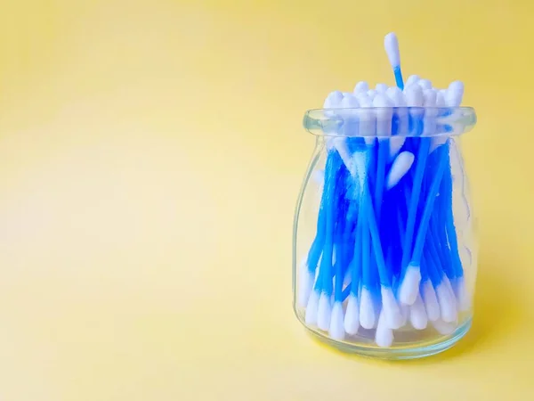 Los palitos de algodón oyen plástico azul sobre un fondo amarillo. Higiene y cuidado personal. Cosmetología y medicina. —  Fotos de Stock