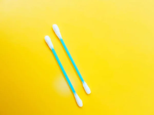 Ear cotton buds are blue on a yellow background. Cosmetology and medicine. Personal hygiene and care. — Stock Photo, Image