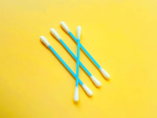 Ear cotton buds are blue on a yellow background. Cosmetology and medicine. Personal hygiene and care. — Stock Photo, Image