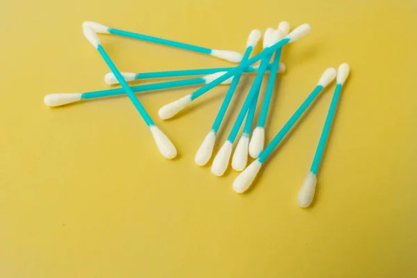 Ear cotton buds are blue on a yellow background. Cosmetology and medicine. Personal hygiene and care. — Stock Photo, Image