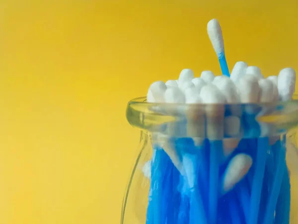 Los palitos de algodón oyen plástico azul sobre un fondo amarillo. Higiene y cuidado personal. Cosmetología y medicina. — Foto de Stock