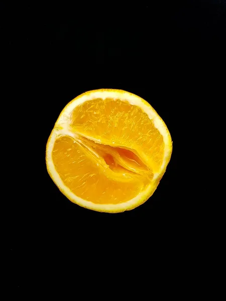 Um símbolo da vagina. O conceito de sexo. Laranja suculenta brilhante em um fundo preto . — Fotografia de Stock