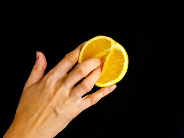 Conceito sexual. Um símbolo da vagina. Dedos em uma laranja em um fundo preto . — Fotografia de Stock