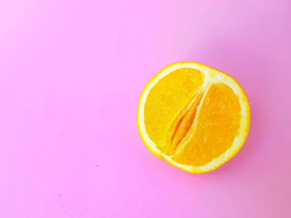 Bright juicy orange on a pink background. A vagina symbol. The concept of sex. Womens personal hygiene. — Stockfoto