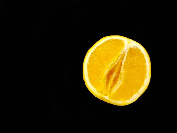 A vagina symbol. The concept of sex. Bright juicy orange on a black background. — Stock fotografie