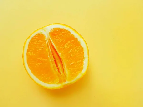 Bright juicy orange on a yellow background. A vagina symbol. The concept of sex. Womens personal hygiene. — Stockfoto