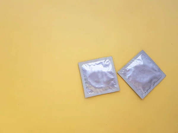 Kondom dengan latar belakang kuning. Konsep seks yang aman dan perlindungan dari infeksi menular seksual. — Stok Foto