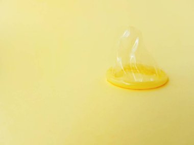 Sarı arka planda prezervatif. Cinsel yolla bulaşan enfeksiyonlardan korunma ve güvenli seks kavramı.
