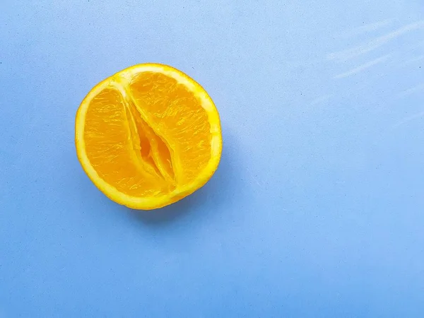 Bright juicy orange on a blue background. A vagina symbol. The concept of sex. Womens personal hygiene. — Photo