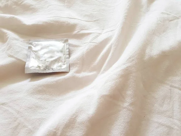 Kondom na bílém pozadí. Koncept bezpečného sexu a ochrany před sexuálně přenosnými infekcemi. — Stock fotografie