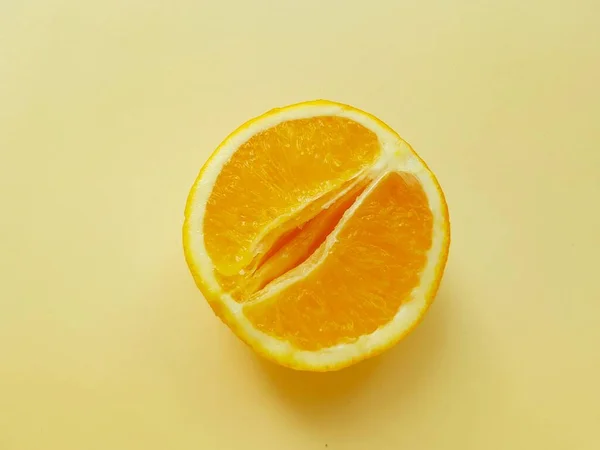 Яскравий соковитий апельсин на жовтому тлі. Символ піхви. Концепція сексу. Особиста гігієна жінок . — стокове фото