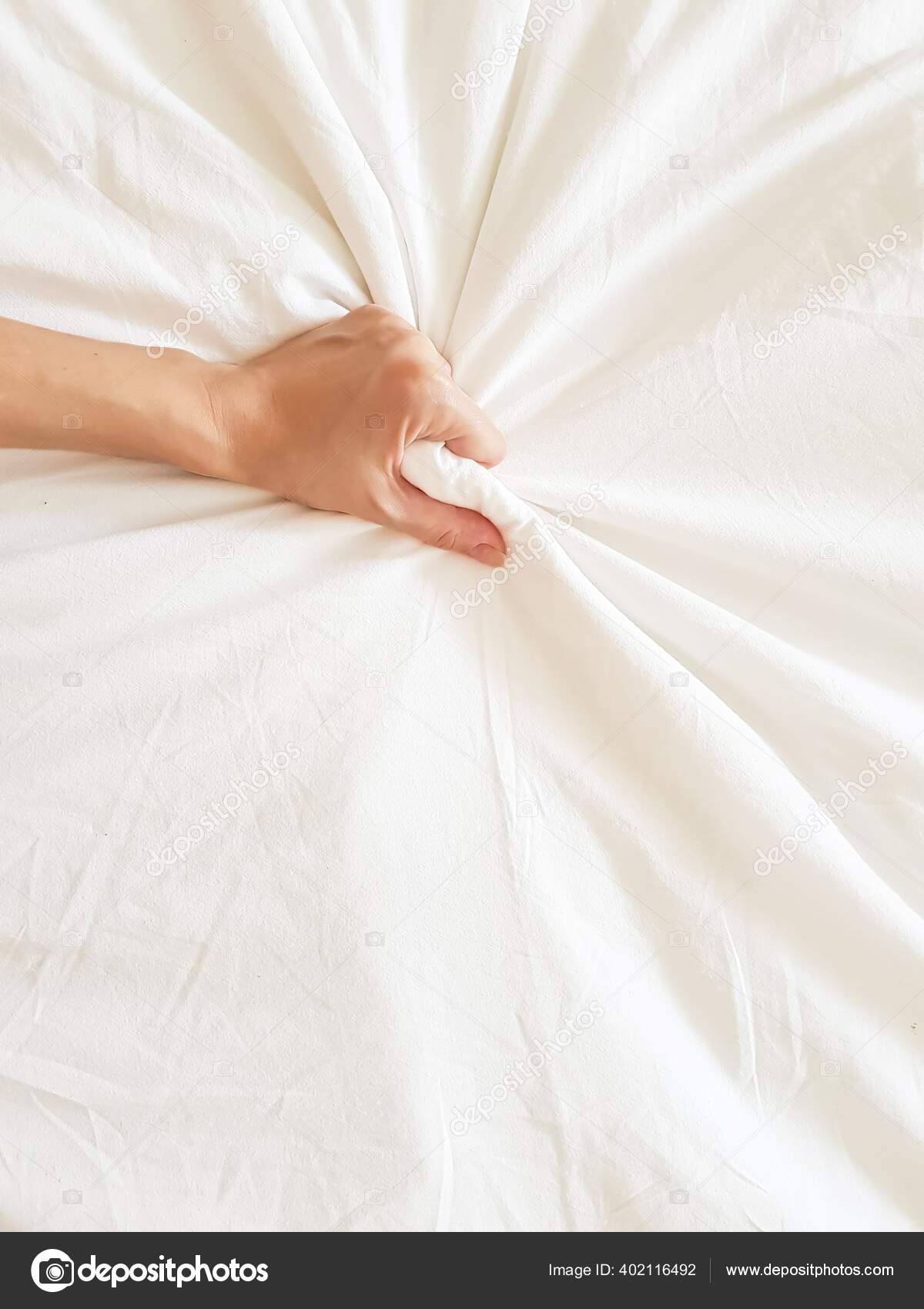 Close up sexy woman hand pulling and squeezing white sheets in ecstasy in bed. Orgasm on white
