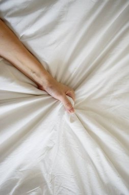 Seksi bir kadının elini çek ve yatakta beyaz çarşafları sık. Beyaz yatakta orgazm. Seks ve erotik kavram.