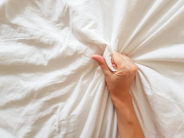 Close up sexy woman hand pulling and squeezing white sheets in ecstasy in bed. Orgasm on white bed. Sex and erotic concept. — Stock Photo, Image