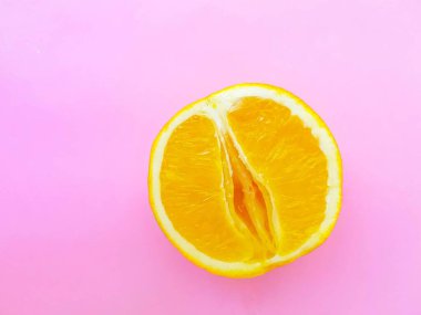 Bright juicy orange on a pink background. A vagina symbol. The concept of sex. Womens personal hygiene.
