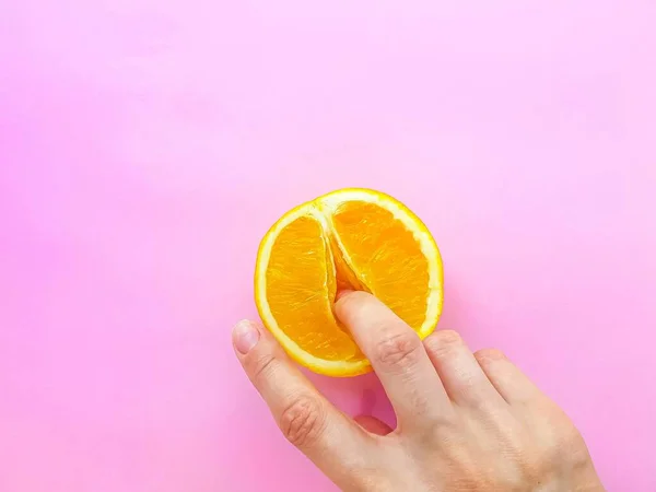 A vagina symbol. The concept of sex. Finger on an orange on a pink background. ストックフォト