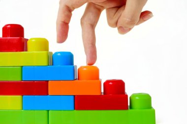 Adım adım en tepeye. Başarılı finansal büyüme konsepti. Kadınlar, beyaz arka planda çok renkli bir çocuk tasarımcısının merdivenlerine el basar..