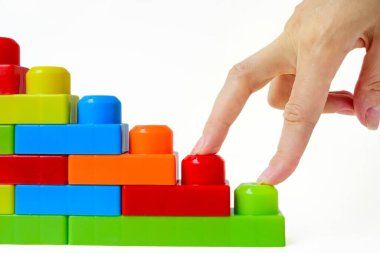 Adım adım en tepeye. Başarılı finansal büyüme konsepti. Kadınlar, beyaz arka planda çok renkli bir çocuk tasarımcısının merdivenlerine el basar..