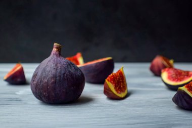 Koyu bir arka planda, ahşap yüzeyde parlak olgun incirler..