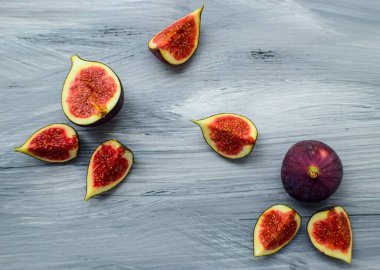 Koyu bir arka planda, ahşap yüzeyde parlak olgun incirler..