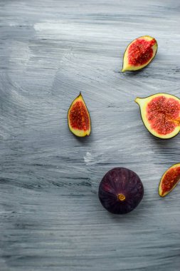 Koyu bir arka planda, ahşap yüzeyde parlak olgun incirler..