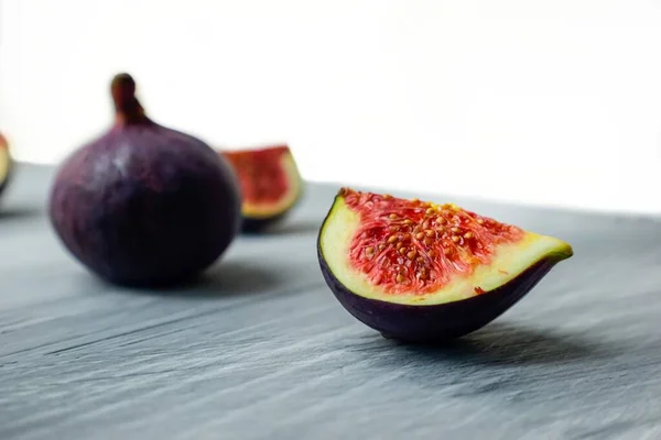 Higos maduros brillantes en la superficie de madera en la parte posterior de un fondo oscuro. — Foto de Stock