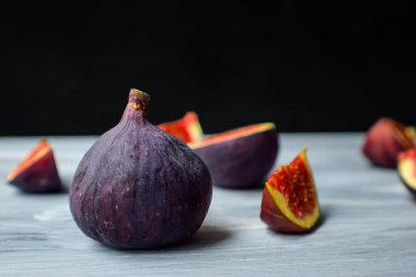 Koyu bir arka planda, ahşap yüzeyde parlak olgun incirler..