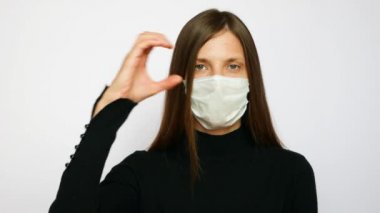 Koruyucu maske takan genç güzel bir kadın sağır için COVID-19 işaret dili olduğunu söylüyor.